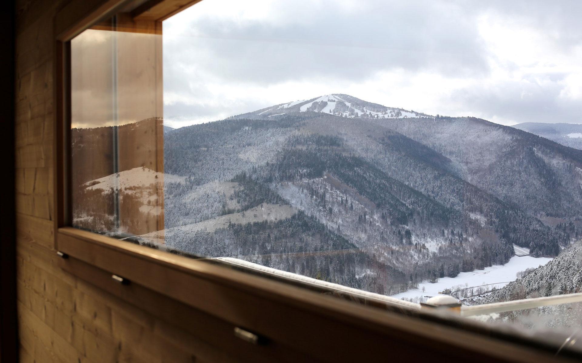 Fenêtre du chalet donnant sur les montagnes enneigées des Vosges d'Alsace.